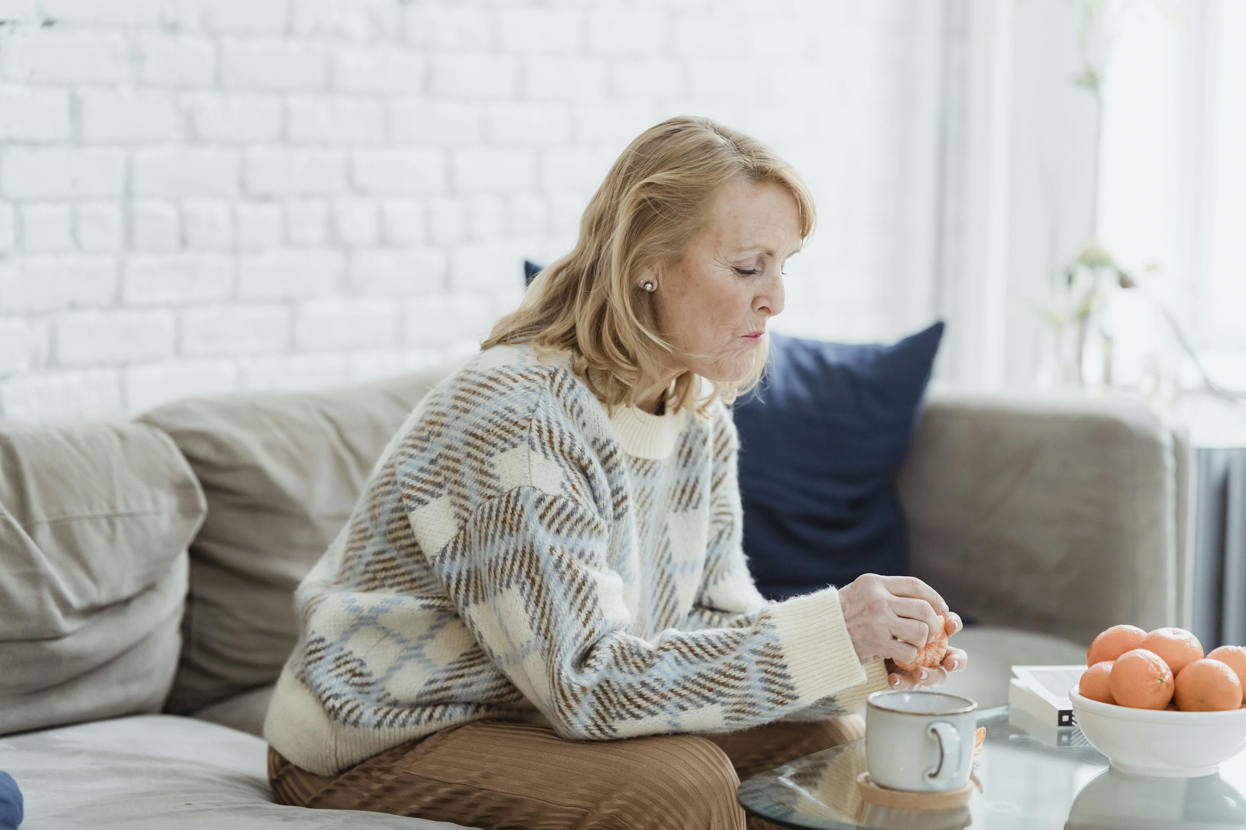 A serene morning with a woman enjoying coffee and peeling an orange on a cozy couch.
